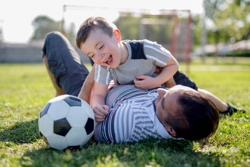 Man with child playing football on field